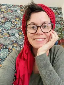 Portrait de Céline Caille, sophrologue, avec un foulard rouge et lunettes.