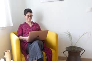 Femme souriante travaillant sur ordinateur portable jaune