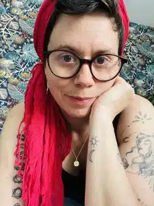 Céline Caille, sophrologue, avec lunettes et foulard rouge, visage proche, fond coloré.