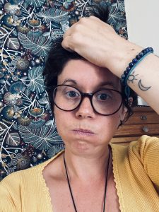 Femme à lunettes tenant ses cheveux devant un tissu floral